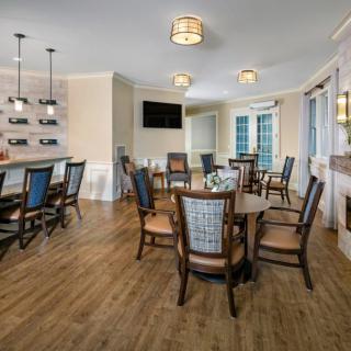 A contemporary dining area featuring wooden flooring, modern lighting fixtures, and a bar section with a television.