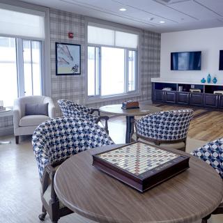 A modern living room with patterned chairs, a board game on the table, and a wall-mounted television.
