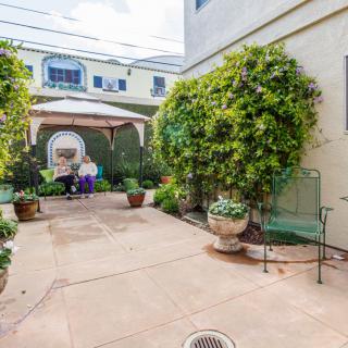 A cozy courtyard with lush greenery and a gazebo for relaxing in an outdoor seating area.