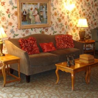 A cozy living room with a floral wallpaper, featuring a sofa adorned with red decorative pillows and wooden coffee tables.