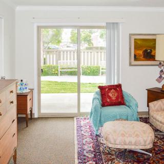 A cozy living room with an armchair, rug, and a sliding glass door leading to a green lawn.