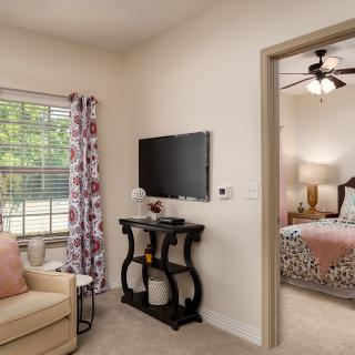 A cozy living room with a television and sofa, leading into a tastefully decorated bedroom.