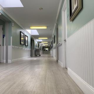 A clean and well-lit hospital hallway with art on the walls and skylights above.