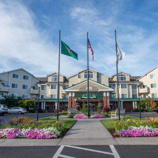 A landscaped entrance to a multi-story building with flags flying at the front.