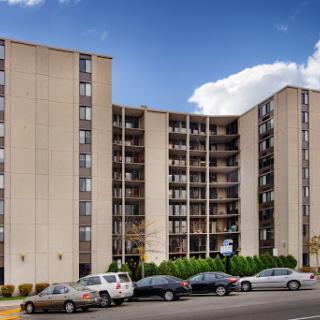 A modern residential apartment building featuring multiple stories and a parking area.