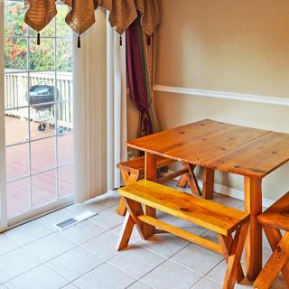 A cozy dining area with a wooden table and benches, next to a sliding glass door leading to the deck.