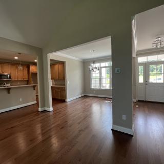 Spacious interior with hardwood floors and natural lighting, featuring an open living area and kitchen.