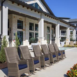 A modern outdoor patio with stylish chairs in front of a contemporary building.
