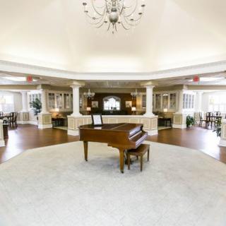 A spacious and elegant lobby with a grand piano in the center.