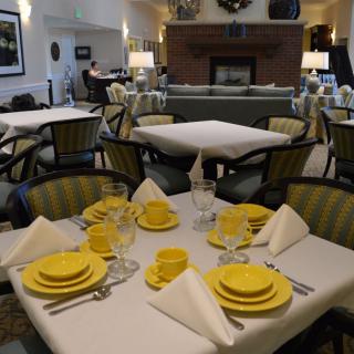 An elegantly set dining area with yellow dishware and comfortable seating.