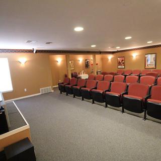 A spacious home theater with multiple rows of red chairs facing a projector screen.