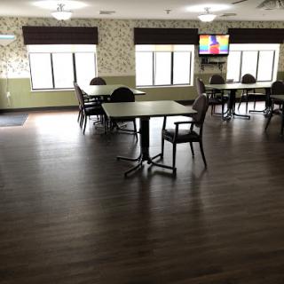 A spacious dining area featuring tables and chairs, illuminated by natural light from large windows.