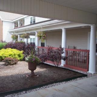 A covered porch with columns and landscaping in front of a house.