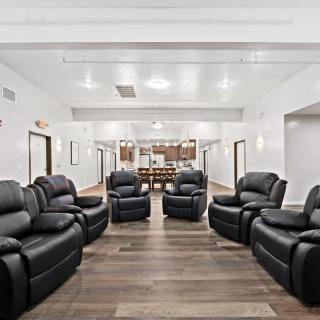 A modern living room with black reclining sofas and wooden flooring.