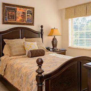 A cozy and elegantly decorated bedroom featuring a wooden bed frame, soft bedding, and warm lighting.