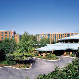A hotel building surrounded by landscaped gardens and a driveway.