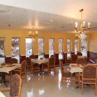 An elegant dining area with multiple tables and chandeliers, featuring large windows.