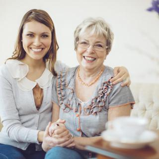 Two women smiling and sitting together indoors.