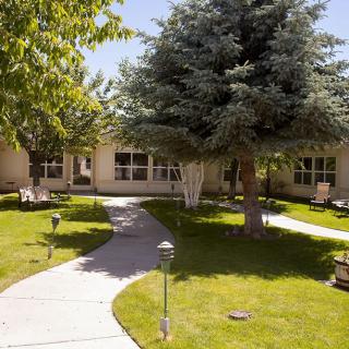 A serene garden with a winding pathway and lush greenery in front of a building.