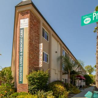 A residential building on a street corner with a visible street sign and landscaping in front.