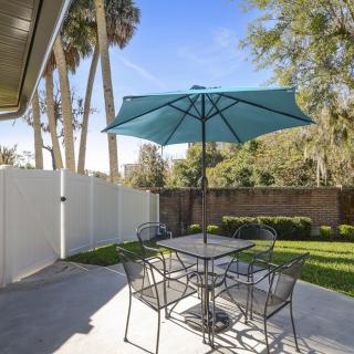 A backyard patio with a table, chairs, and a large umbrella under a clear blue sky.