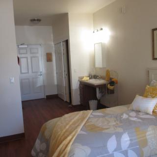 A cozy bedroom with a neatly made bed, soft lighting, and warm decor.