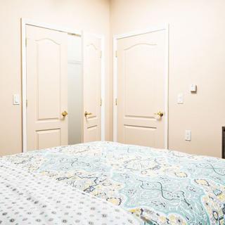 A neatly arranged bedroom featuring two closed doors and a bed with patterned bedding.