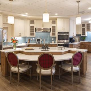 A modern kitchen with an island counter, pendant lighting, and wooden flooring.