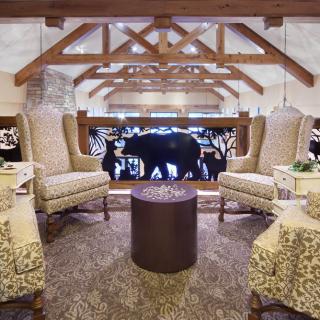 A cozy lounge area featuring armchairs, a round table, and rustic wooden beams.