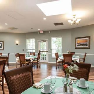 A spacious and elegantly decorated dining room with neatly arranged tables and chairs, filled with natural light from large windows.