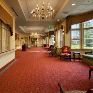 A spacious and elegantly decorated lobby featuring chandeliers, plush seating, and a vibrant carpet.