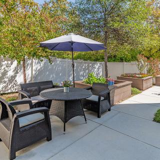 A cozy patio area with seating, a table, and an umbrella in a garden setting.