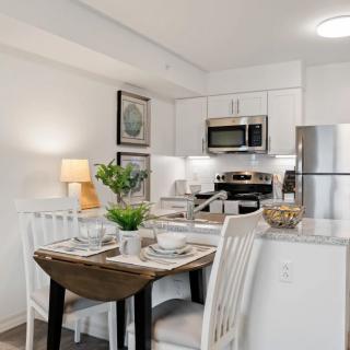 A modern kitchen and dining area with white cabinets, a set table, and stainless steel appliances.