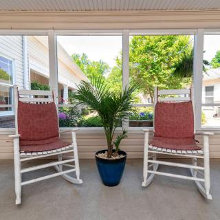 A cozy porch with two white rocking chairs and a potted plant.