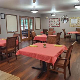 A cozy dining area with tables covered in pink tablecloths and wooden chairs.