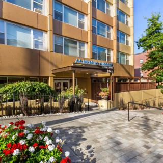 Entrance to a hotel with surrounding greenery and flowers.