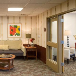 A cozy waiting room with a sofa, coffee table, and colorful artwork on the wall.