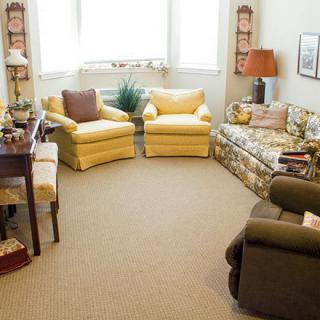 A cozy living room with armchairs, a sofa, and a lamp.