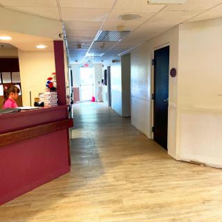 A brightly lit hallway with a reception desk and corridor.