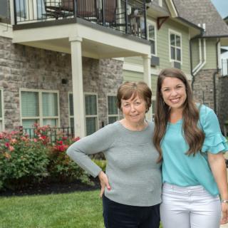 Two people standing together outside a house.