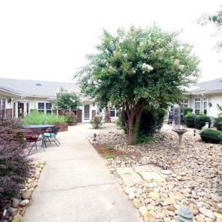 A serene courtyard with a central pathway, surrounded by lush landscaping and buildings.