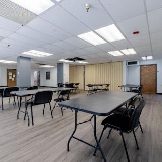 A spacious, empty meeting room with tables and chairs arranged for an event.
