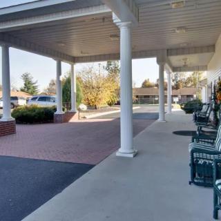 A covered walkway with benches and columns leading to a driveway.