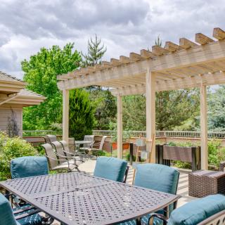 A spacious outdoor patio featuring a pergola and comfortable seating area surrounded by lush greenery.