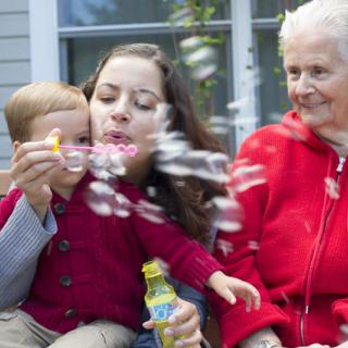 A family enjoying time together outdoors, blowing bubbles.