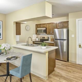A modern apartment kitchen with an open layout, featuring stainless steel appliances and a cozy dining area.