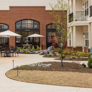 A courtyard with outdoor seating and umbrellas beside an apartment building.