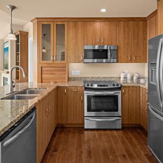 A modern kitchen featuring wooden cabinets, stainless steel appliances, and a spacious layout with a granite countertop.