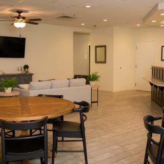 A modern living and dining area featuring comfortable seating, a television, and a ceiling fan in an open-plan layout.