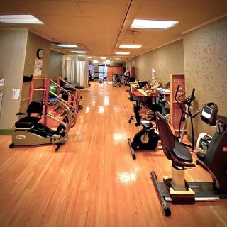 A spacious gym with various exercise equipment and cardio machines on a wooden floor.